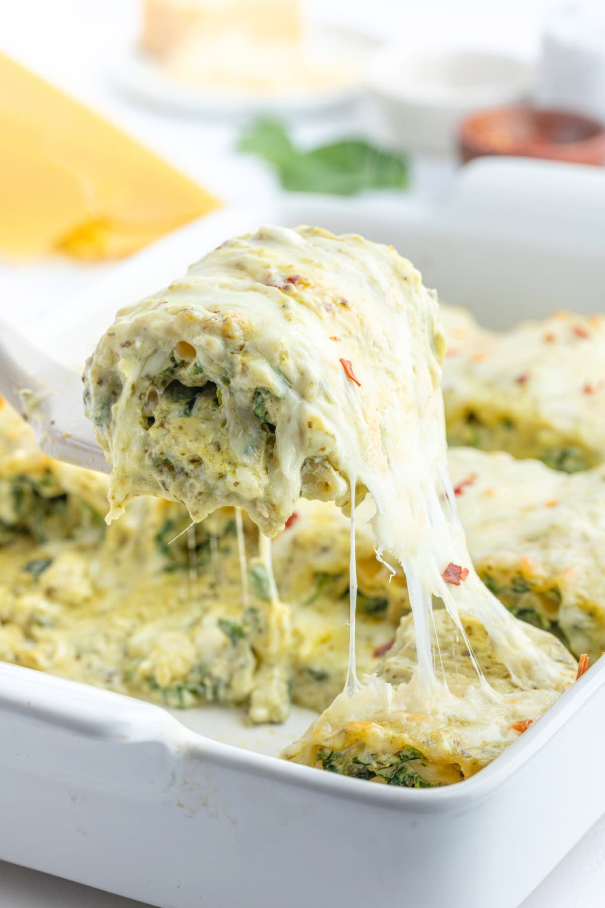 spatula pulling pesto lasagna roll from casserole dish