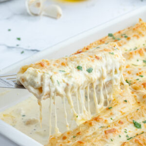 spatula lifting up chicken manicotti alfredo out of pan