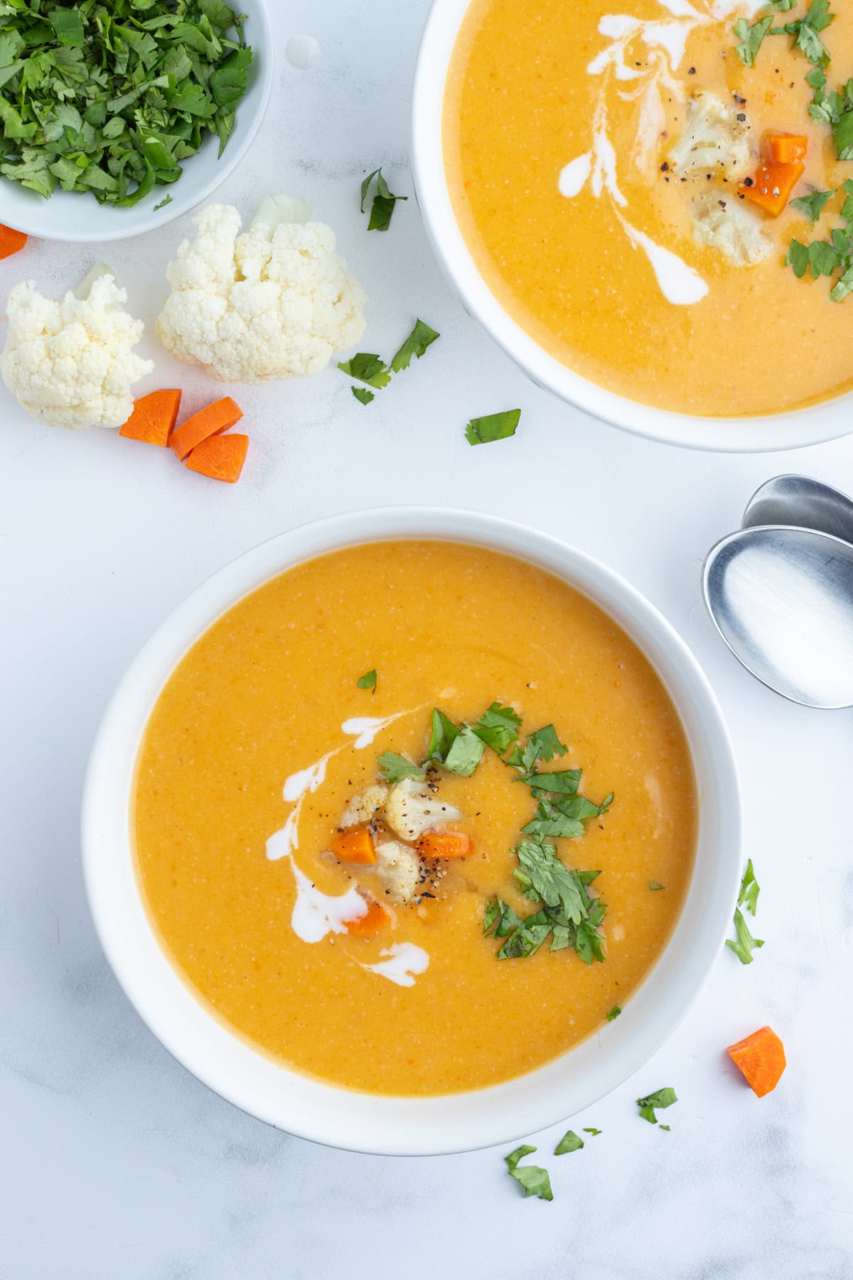 overhead shot of two bowls of cauliflower and sweet potato soup