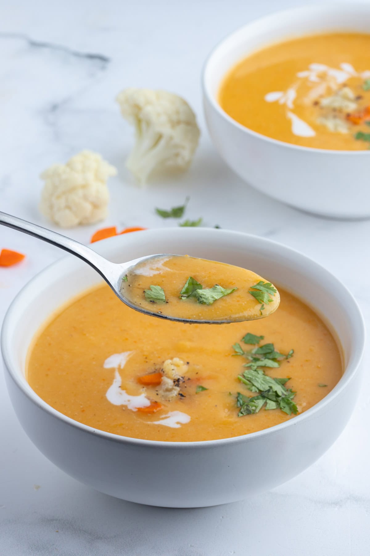 spooning out spoonful of cauliflower and sweet potato soup