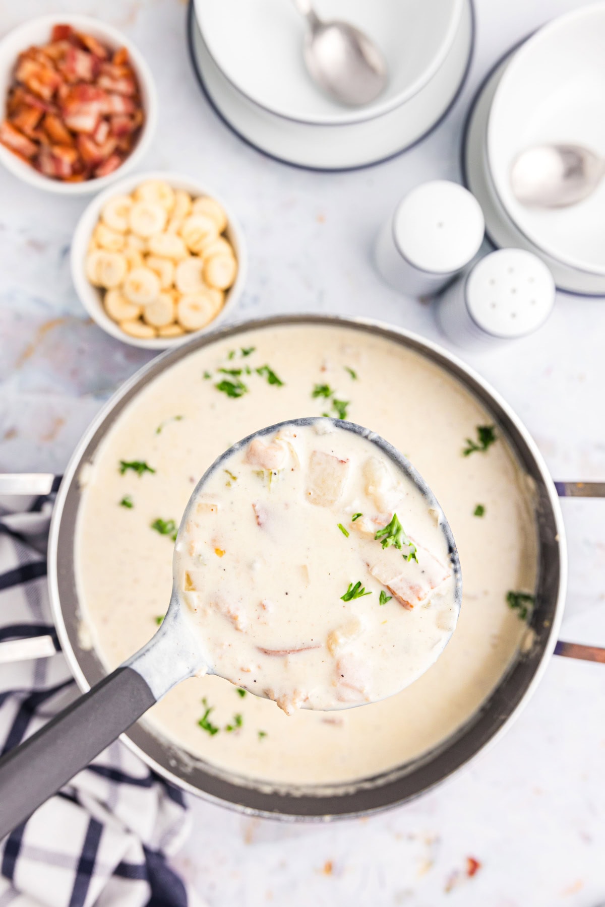 Looking down on pot of clam chowder with ladle full of soup