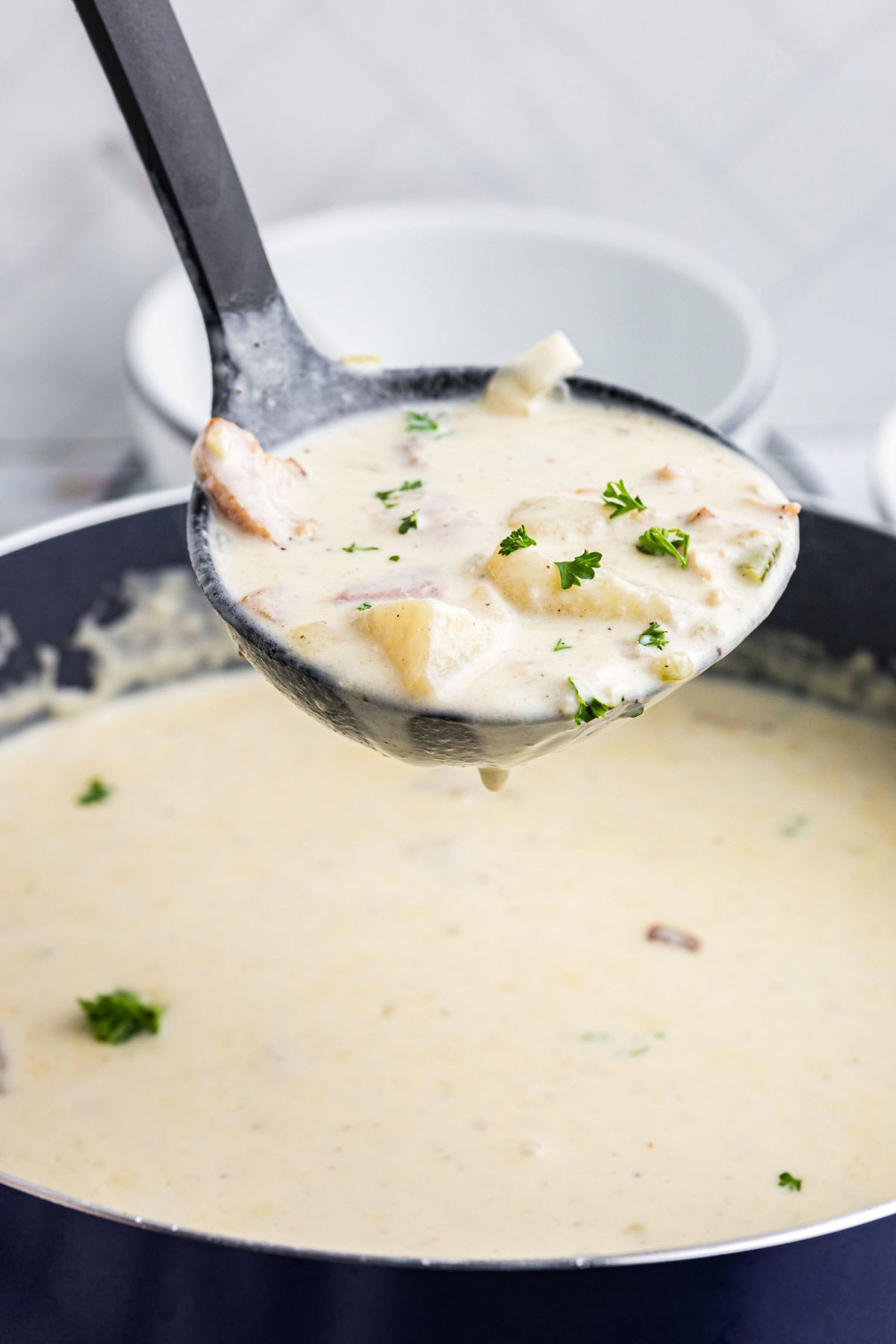 Ladle full of new england clam chowder over pot of chowder